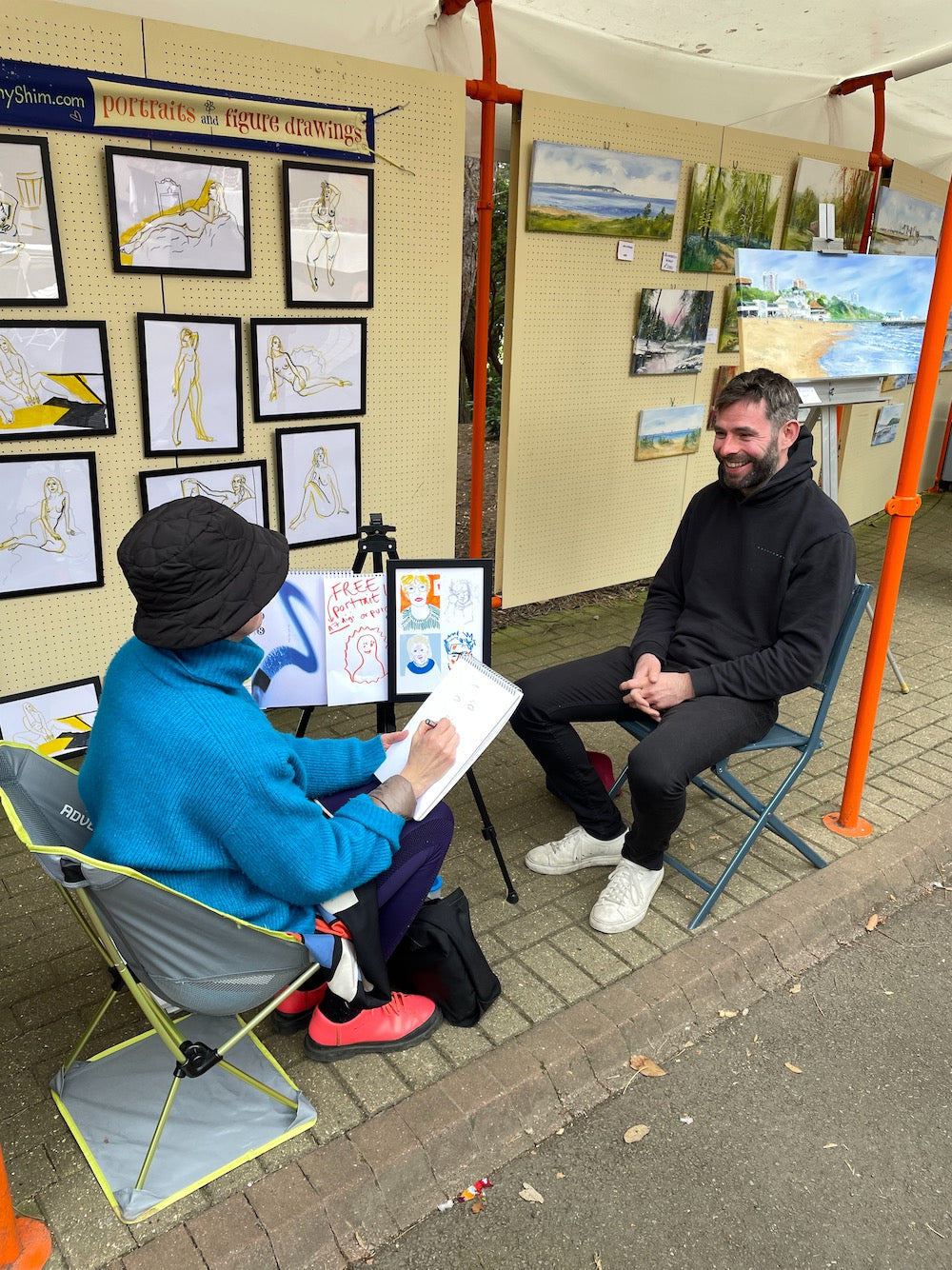 Artist Frankie Sinclair draws customer Steve at the Bournemouth Art Makers Market on 9 April 2023